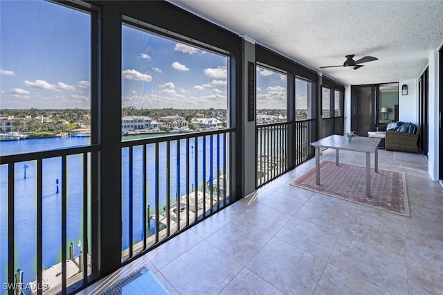 sunroom / solarium featuring a water view and ceiling fan