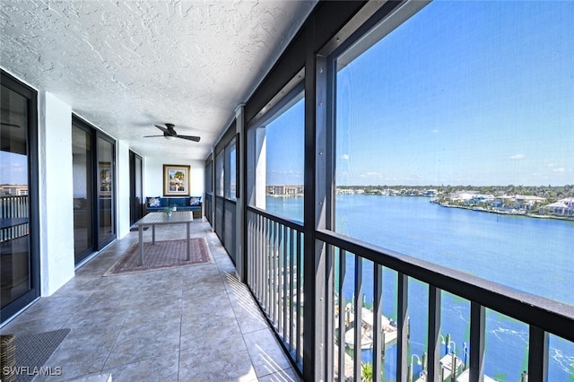 balcony featuring a water view and ceiling fan