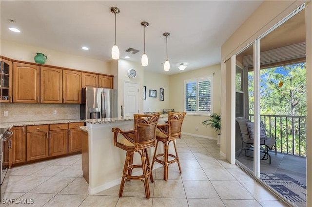 kitchen with light stone countertops, glass insert cabinets, light tile patterned flooring, and stainless steel fridge
