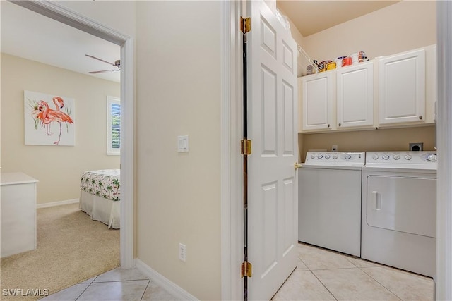 washroom featuring light tile patterned floors, baseboards, a ceiling fan, cabinet space, and washing machine and dryer