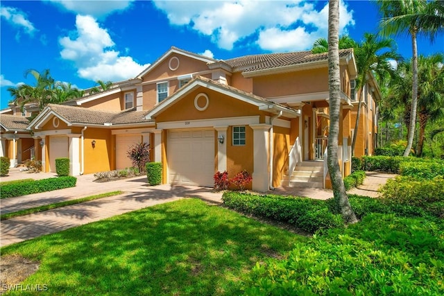 view of front facade with driveway, stucco siding, a tiled roof, and an attached garage