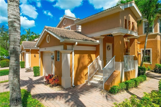 view of front of house with a garage, stucco siding, and a tile roof