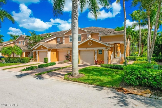 view of front of house featuring driveway, stucco siding, a tile roof, and a garage