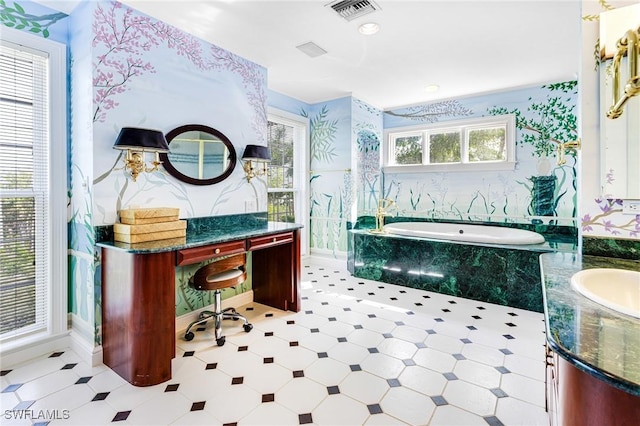 bathroom featuring a relaxing tiled tub, vanity, and a wealth of natural light