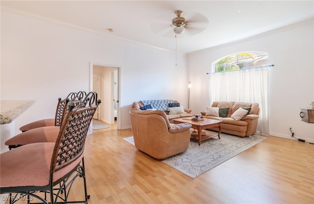 living room with crown molding, ceiling fan, and light hardwood / wood-style flooring