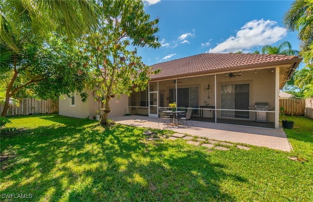 back of property with ceiling fan, a lawn, and a patio