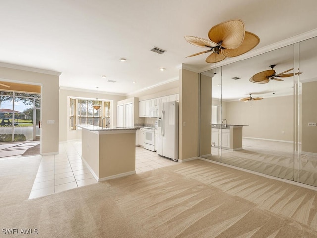 kitchen with crown molding, a center island with sink, light colored carpet, light tile patterned flooring, and white appliances