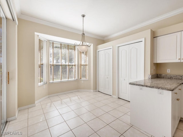 kitchen featuring crown molding, light tile patterned floors, decorative light fixtures, dark stone countertops, and white cabinets