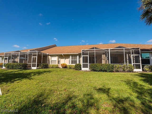 rear view of house with a lanai and a lawn