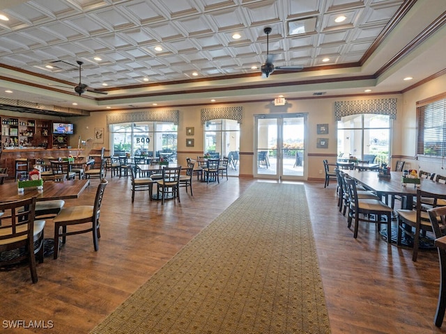 dining space with a tray ceiling, ornamental molding, wood finished floors, and french doors