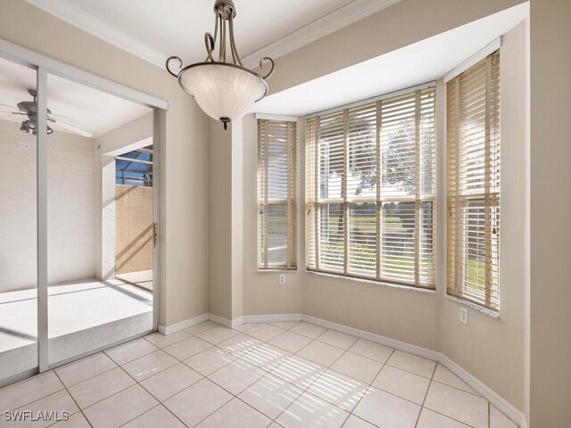 empty room with ornamental molding, light tile patterned flooring, a ceiling fan, and baseboards