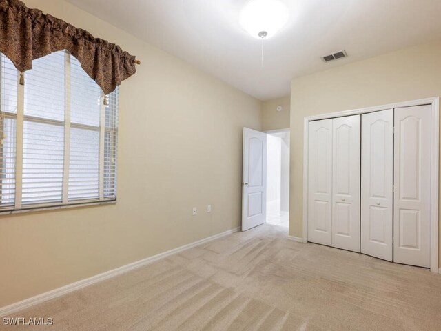 unfurnished bedroom with light colored carpet and a closet