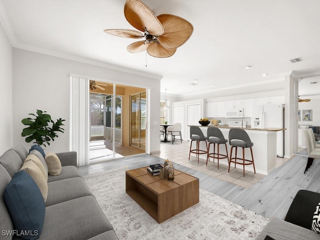 living room featuring ceiling fan, ornamental molding, and visible vents