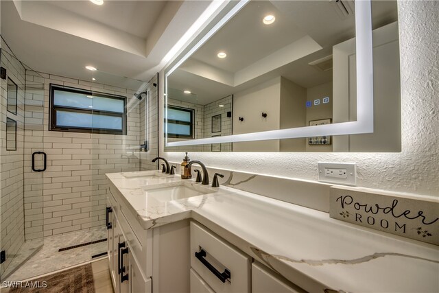 bathroom featuring a raised ceiling, a shower with shower door, and vanity