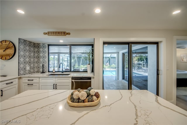 kitchen with dishwasher, light stone counters, and a healthy amount of sunlight