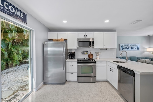 kitchen featuring sink, kitchen peninsula, white cabinetry, appliances with stainless steel finishes, and backsplash