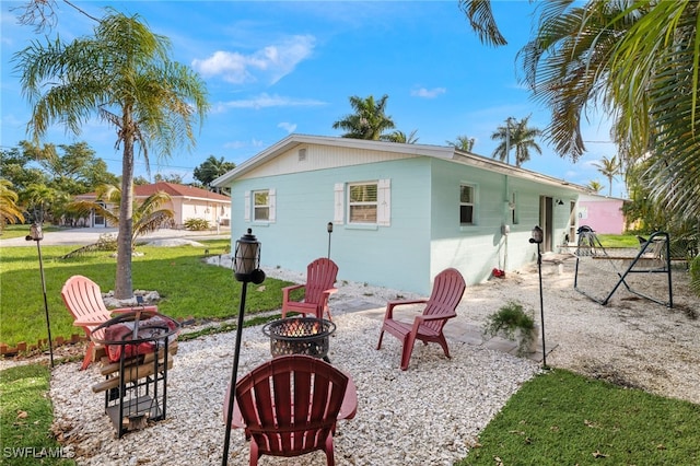 back of property featuring an outdoor fire pit and a yard