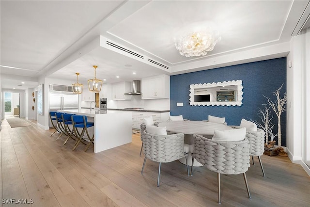 dining space with baseboards, a notable chandelier, and light wood-style floors