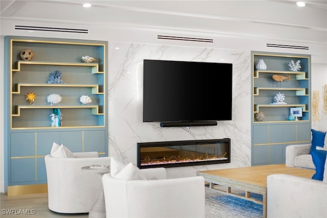 living room featuring a premium fireplace, built in shelves, and wood-type flooring