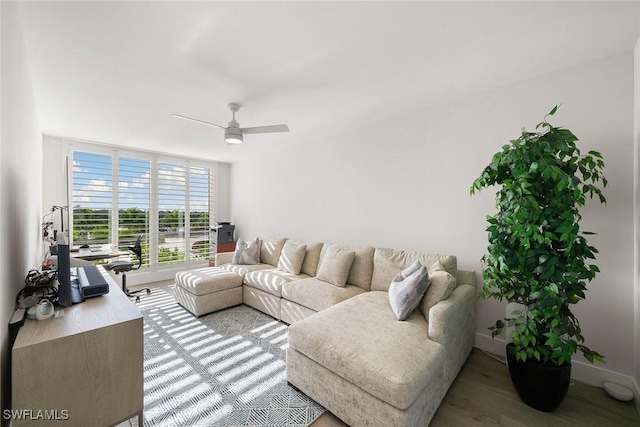 living area with baseboards, a ceiling fan, and wood finished floors
