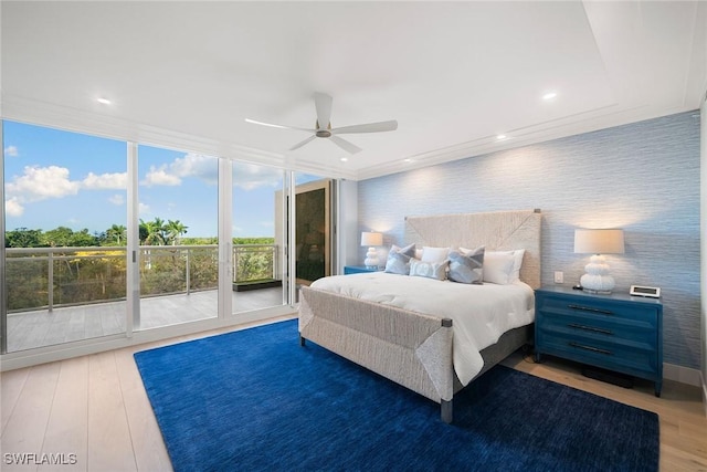bedroom with wood finished floors, a wall of windows, access to exterior, wallpapered walls, and a ceiling fan