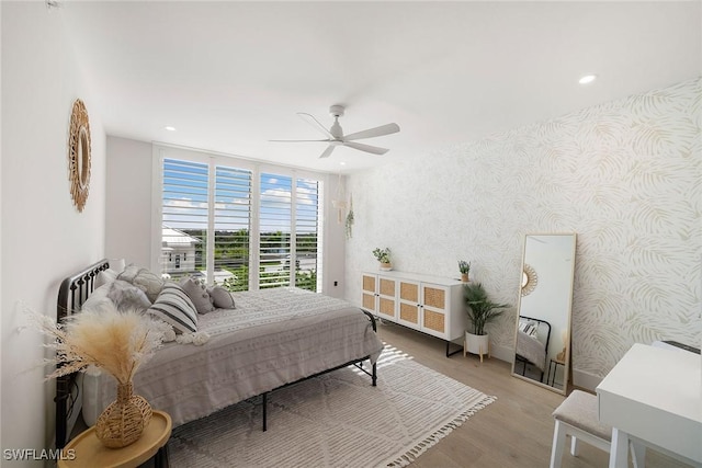 bedroom featuring ceiling fan, floor to ceiling windows, wood finished floors, wallpapered walls, and recessed lighting