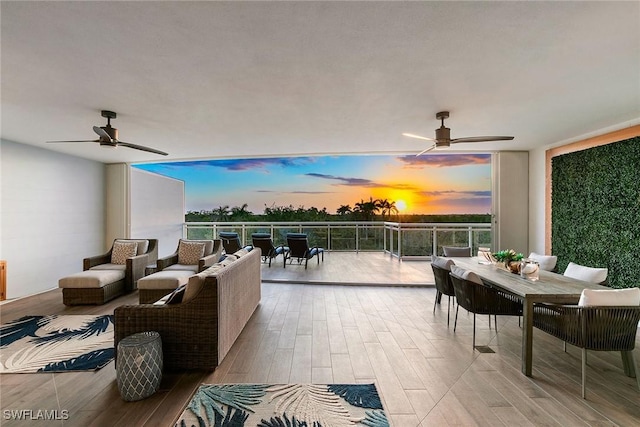 patio terrace at dusk with a ceiling fan, outdoor dining area, outdoor lounge area, and a balcony