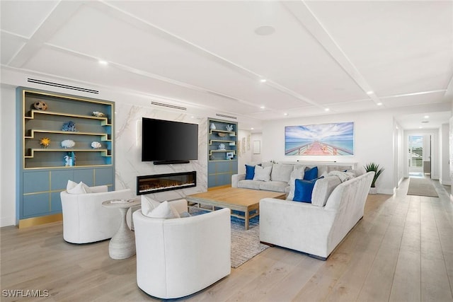 living room featuring baseboards, light wood-style flooring, and a fireplace