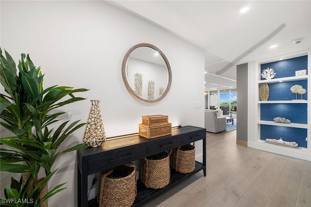 hallway featuring light wood-style floors, baseboards, and built in shelves