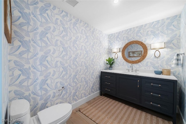bathroom featuring baseboards, toilet, wallpapered walls, and visible vents