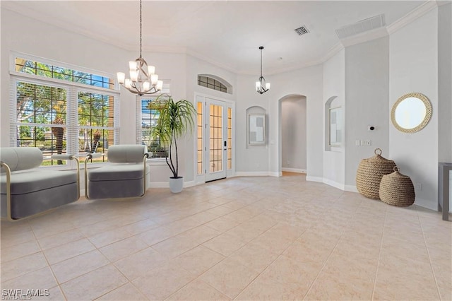 entrance foyer with french doors, ornamental molding, an inviting chandelier, and light tile patterned floors