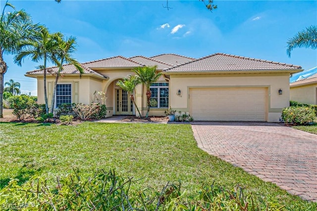 mediterranean / spanish-style house featuring a front yard, a garage, and french doors