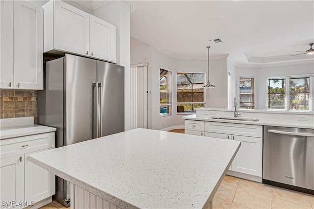 kitchen with white cabinetry, decorative light fixtures, and stainless steel dishwasher