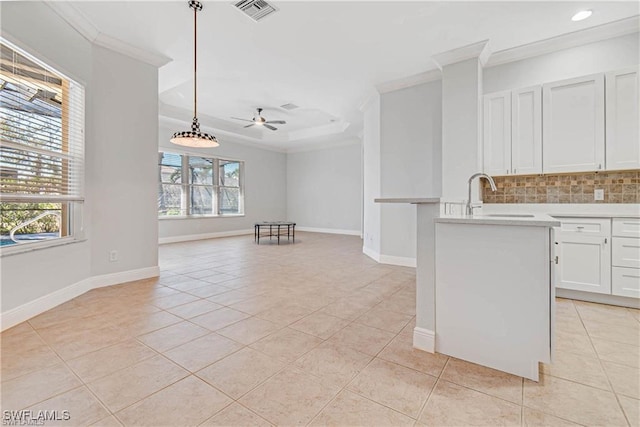 kitchen with ceiling fan, white cabinets, hanging light fixtures, sink, and decorative backsplash