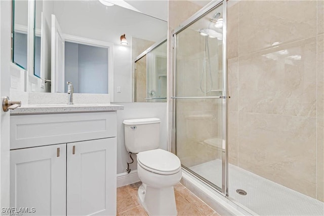 bathroom featuring vanity, toilet, a shower with door, and tile patterned floors