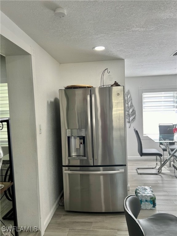 kitchen with light hardwood / wood-style floors, stainless steel fridge, and a textured ceiling