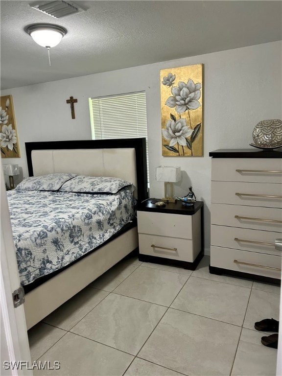 bedroom with a textured ceiling and light tile patterned floors