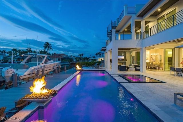 pool at dusk featuring an outdoor living space with a fire pit and a patio area