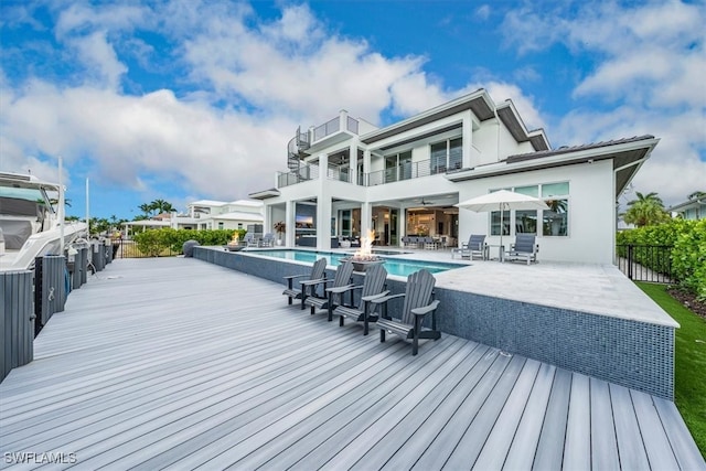 rear view of property featuring a patio, a fenced in pool, and a balcony