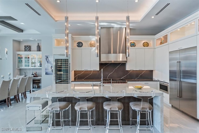 kitchen with a large island, stainless steel appliances, backsplash, and range hood