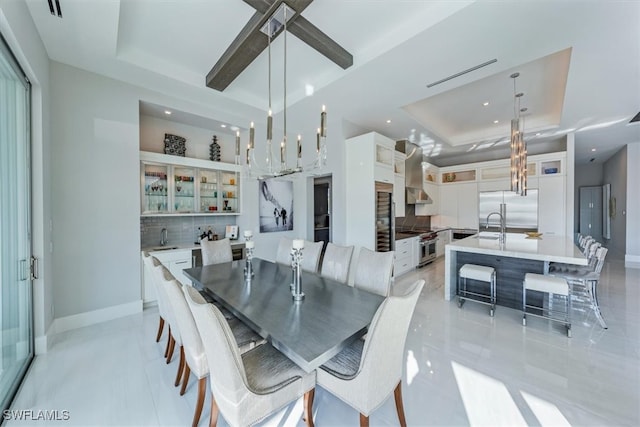 dining space with sink, an inviting chandelier, and a raised ceiling