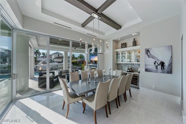 tiled dining space featuring beamed ceiling, wine cooler, and a raised ceiling