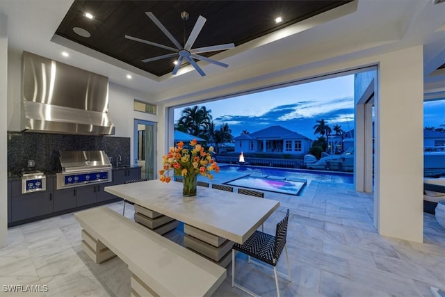 patio terrace at dusk featuring ceiling fan, an outdoor kitchen, area for grilling, and sink