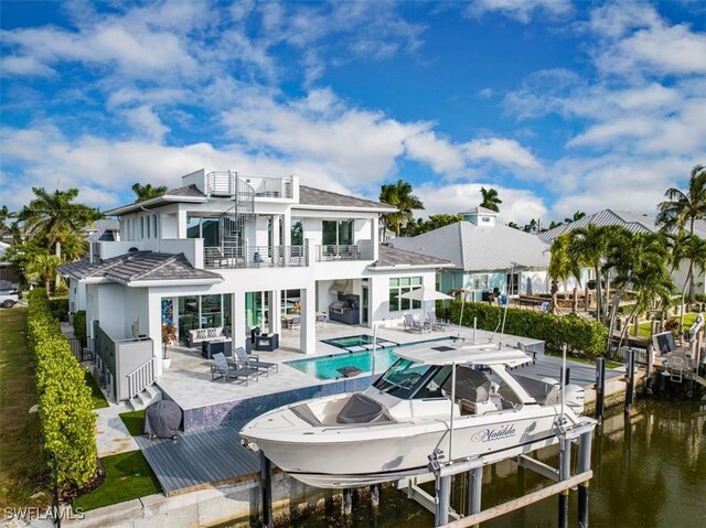 back of property featuring a water view, a balcony, and a patio area