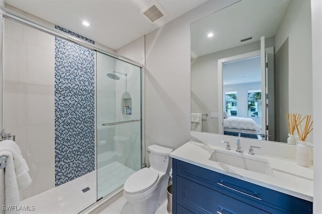 bathroom featuring a shower with door, vanity, and toilet