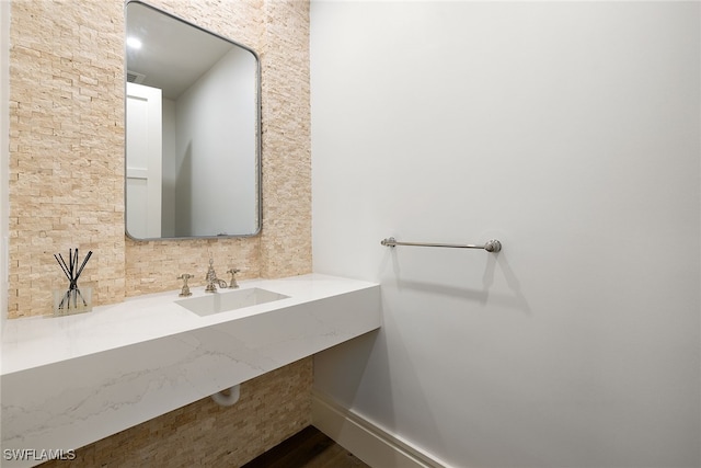 bathroom featuring sink, hardwood / wood-style floors, and tasteful backsplash