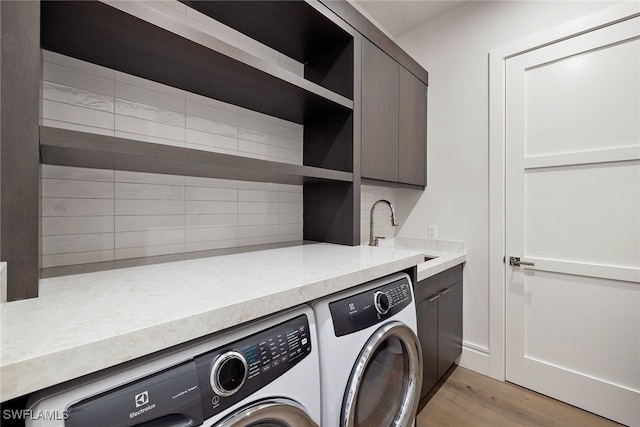 laundry area featuring cabinets, light wood-type flooring, sink, and washing machine and dryer