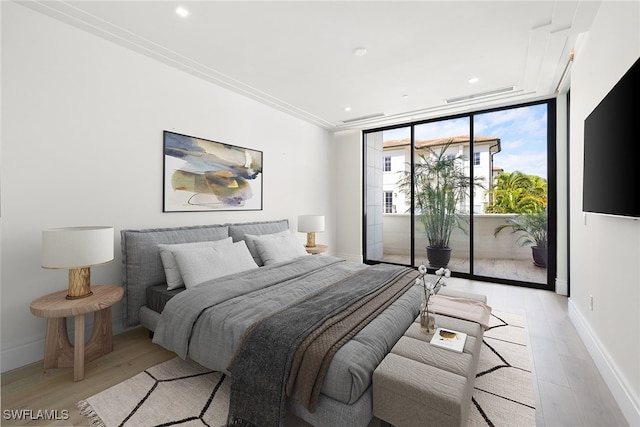 bedroom with access to outside, ornamental molding, light wood-type flooring, and expansive windows