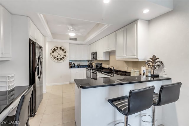 kitchen featuring appliances with stainless steel finishes, kitchen peninsula, and white cabinets