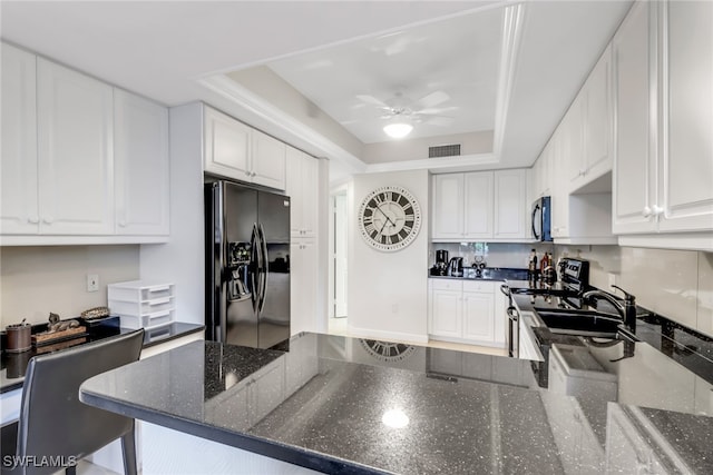 kitchen featuring stainless steel appliances, sink, a raised ceiling, white cabinetry, and ceiling fan